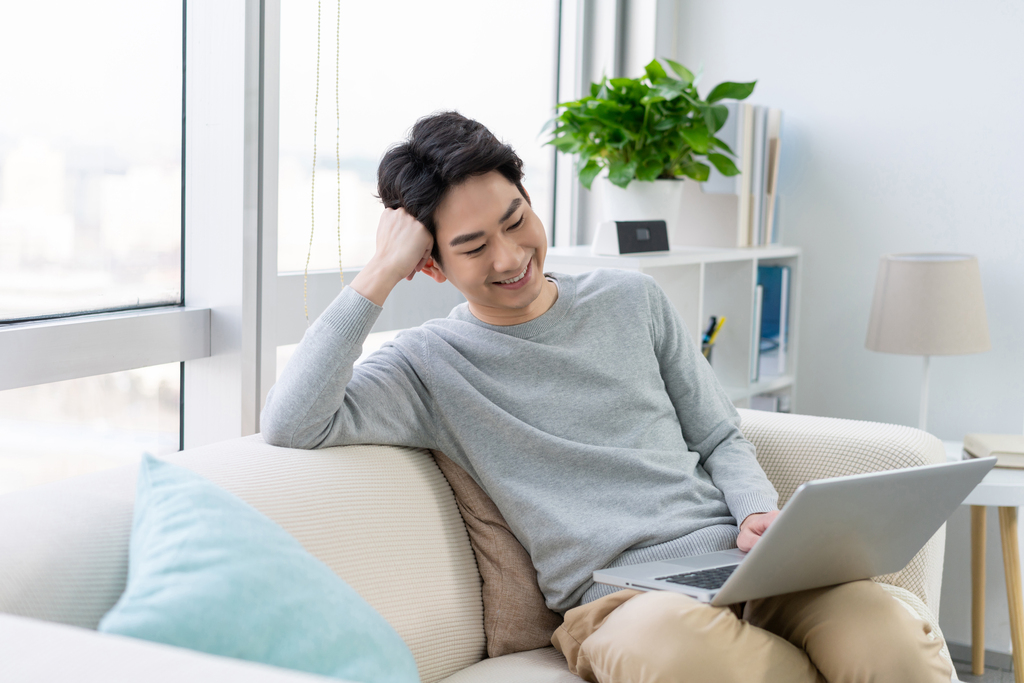 年轻男子在沙发上使用笔记本电脑图片