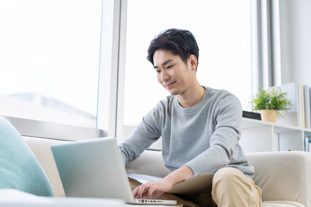 年轻男子在沙发上使用笔记本电脑图片