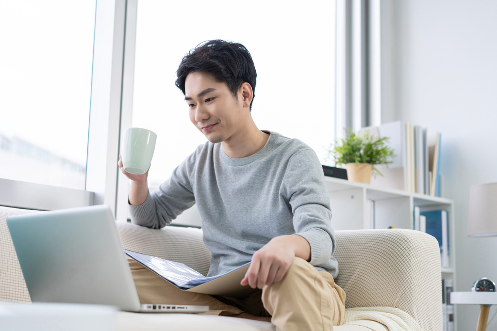 年轻男子在沙发上使用笔记本电脑