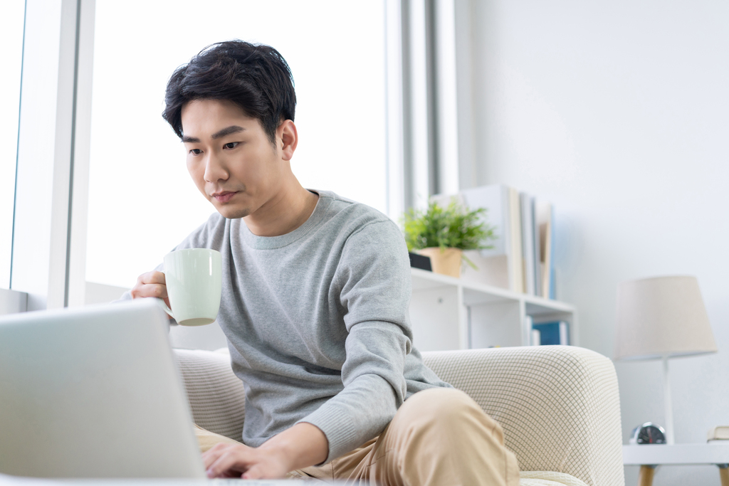 年轻男子在沙发上使用笔记本电脑图片