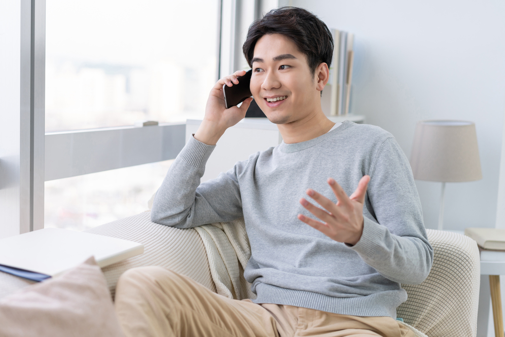 年轻男子坐在沙发上打电话