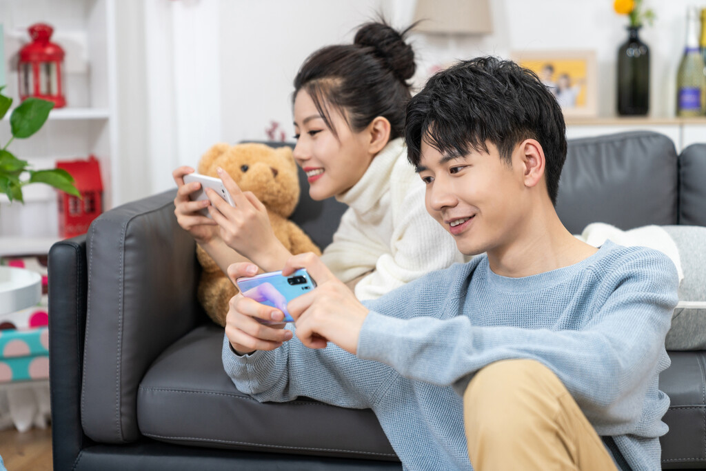 年轻情侣在家玩手机