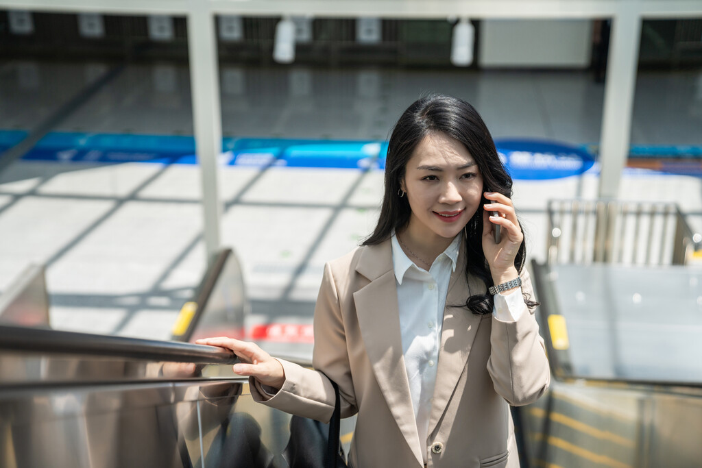 商务女士在机场坐电梯打电话图片