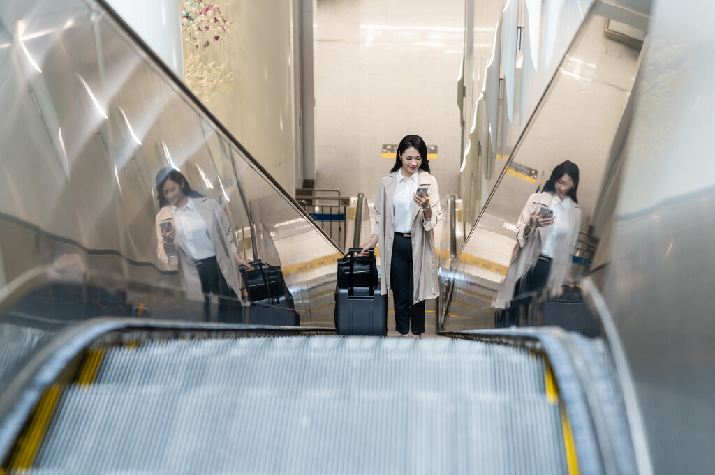 商务女士在机场乘坐电梯使用手机图片