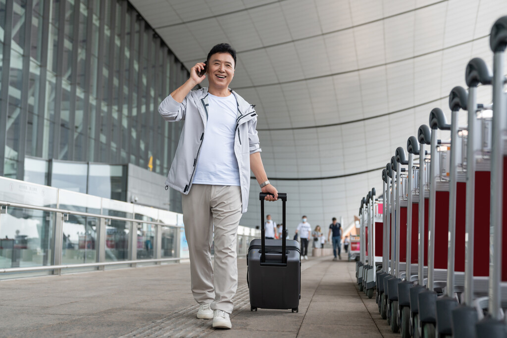 老年男人在机场拉着行李箱打电话图片