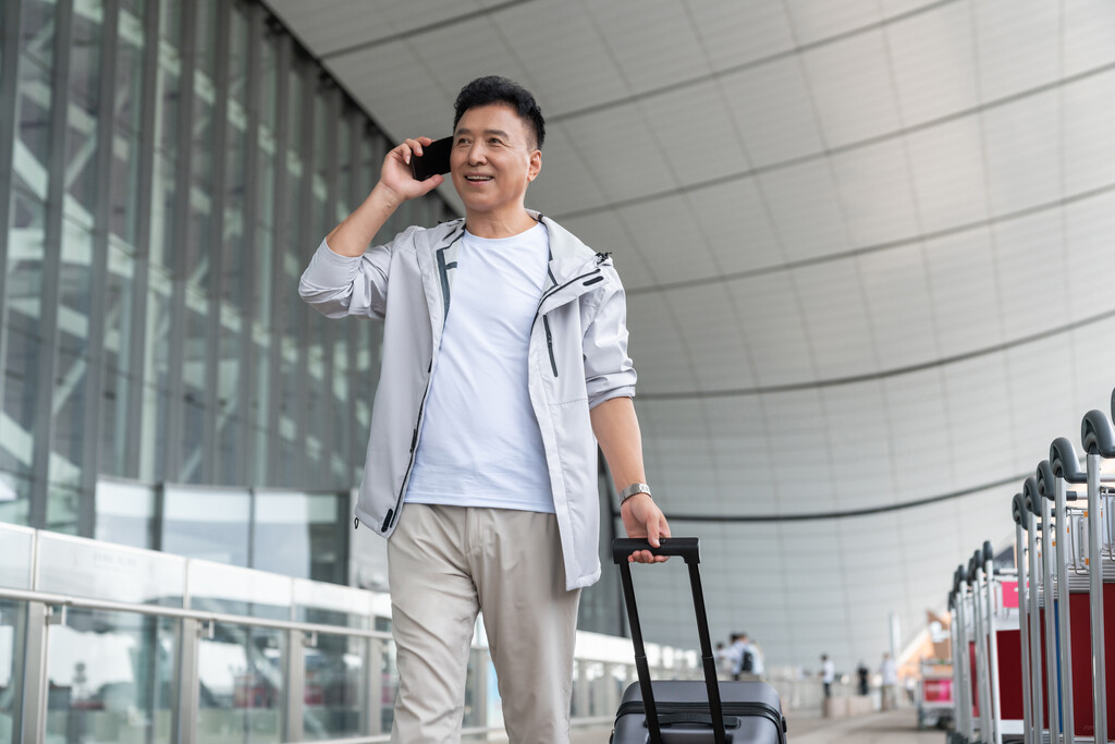 老年男人在机场拉着行李箱打电话图片