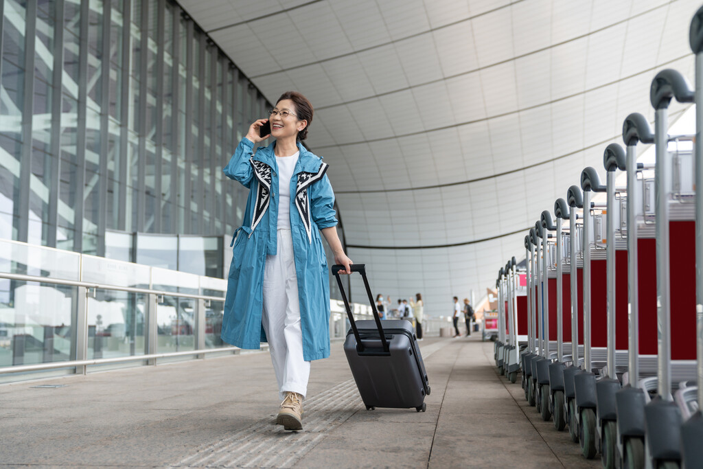 老年女人在机场拉着行李箱打电话图片