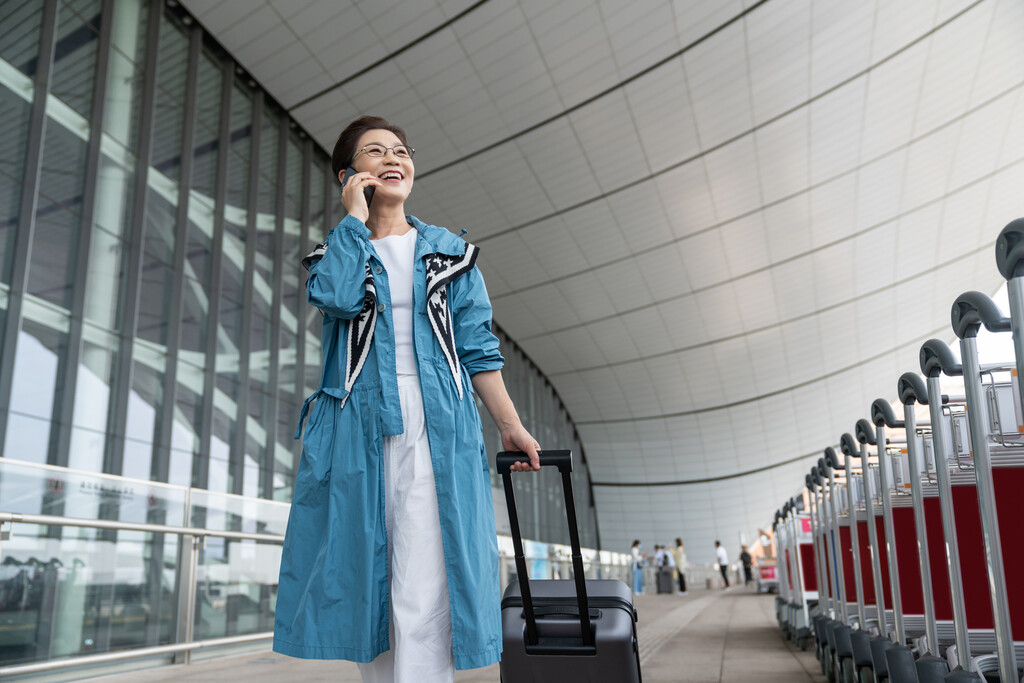 老年女人在机场拉着行李箱打电话图片