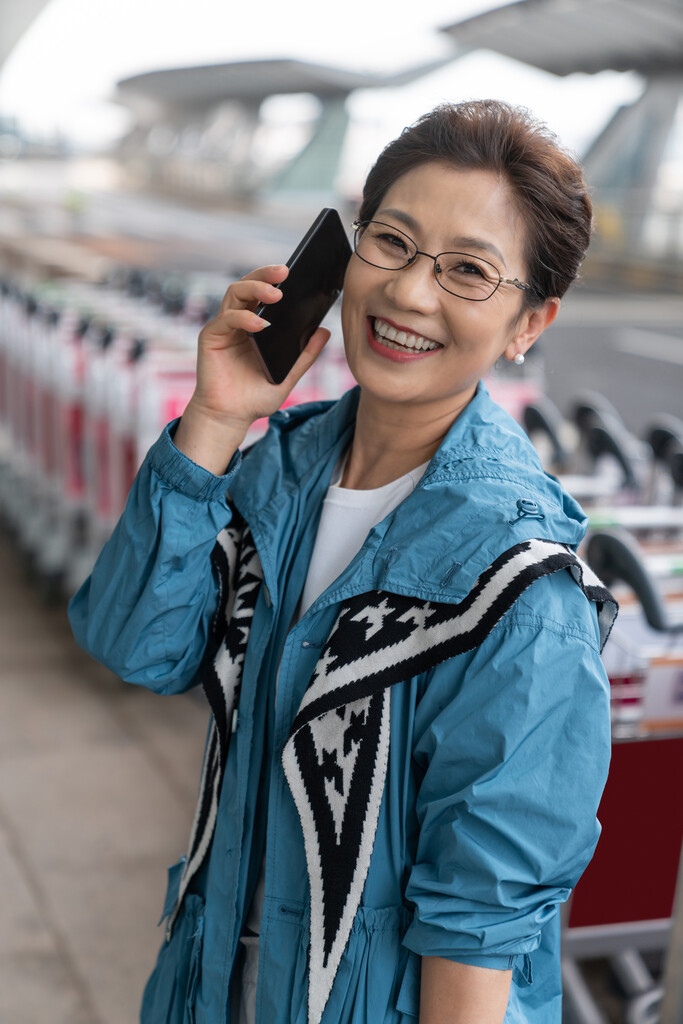 老年女人在机场拉着行李箱打电话图片