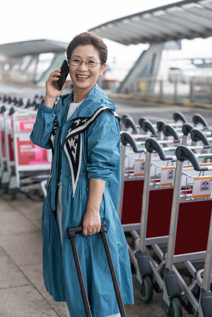 老年女人在机场拉着行李箱打电话图片