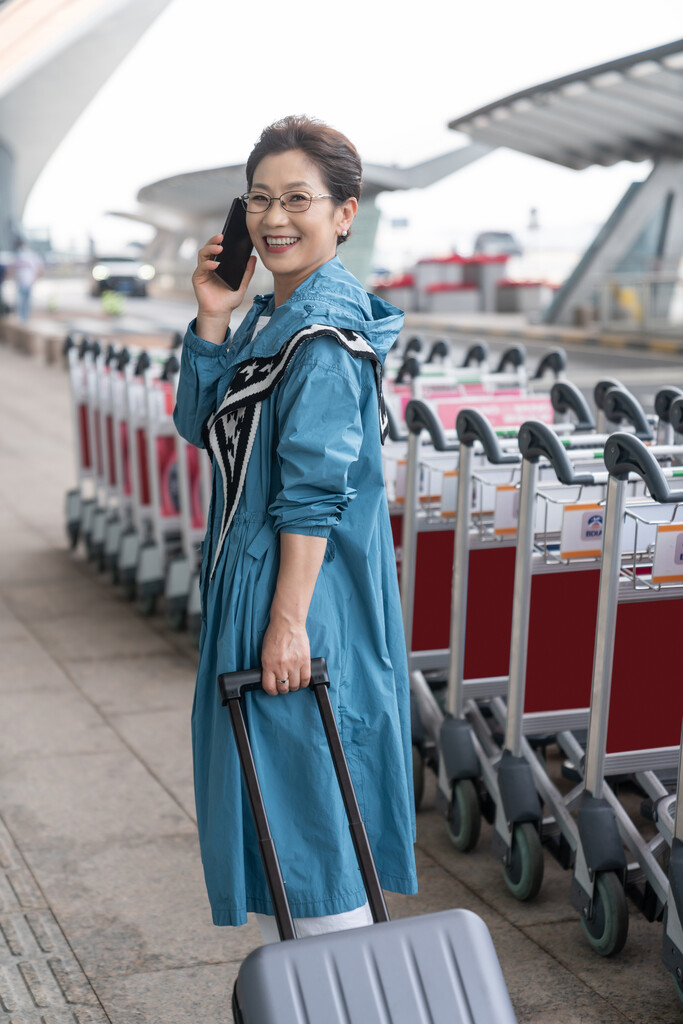 老年女人在机场拉着行李箱打电话