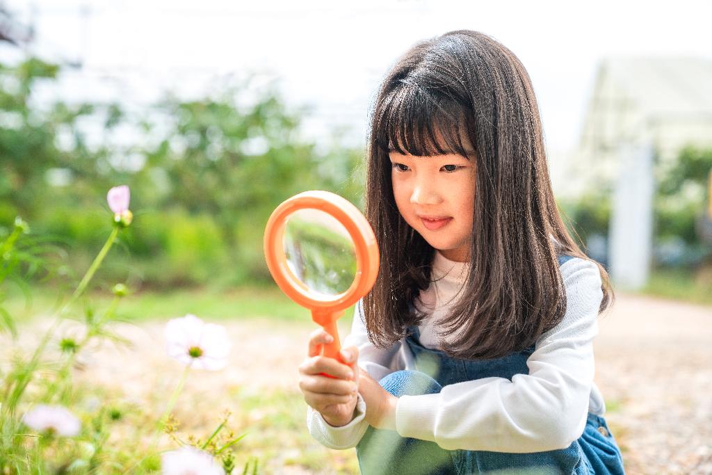 小女孩拿着放大镜观察植物