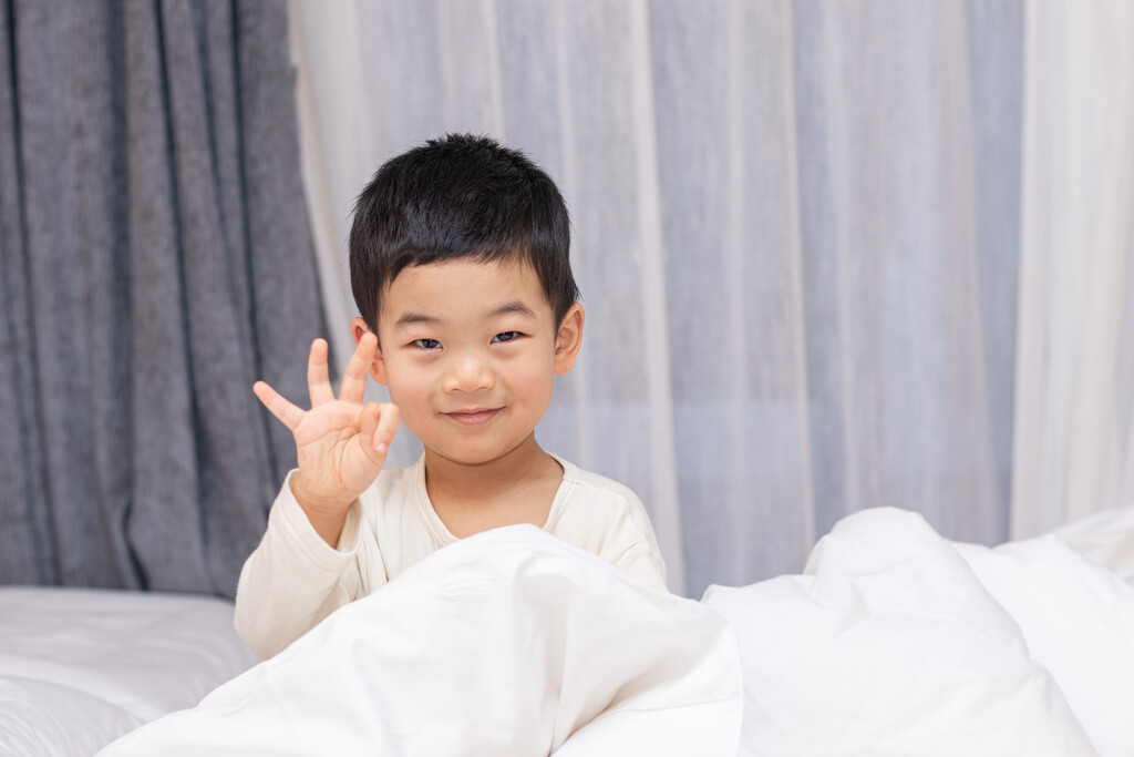 一个小男孩坐在舒适的床上开心笑