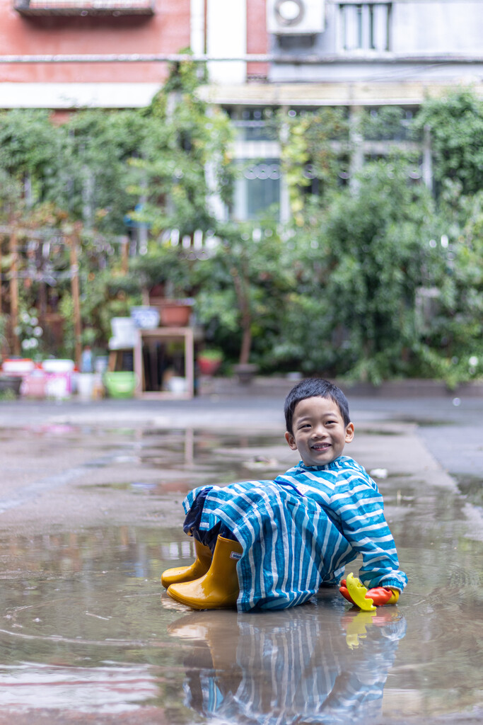 快乐的小男孩雨后在水坑玩耍