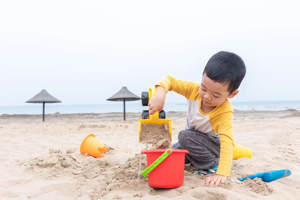 快乐的小男在海边玩沙子图片