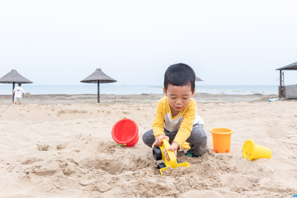 快乐的小男在海边玩沙子图片