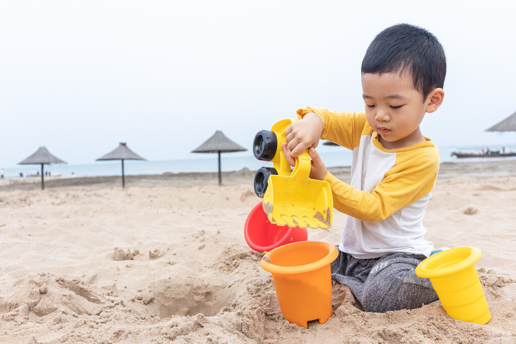 快乐的小男在海边玩沙子图片