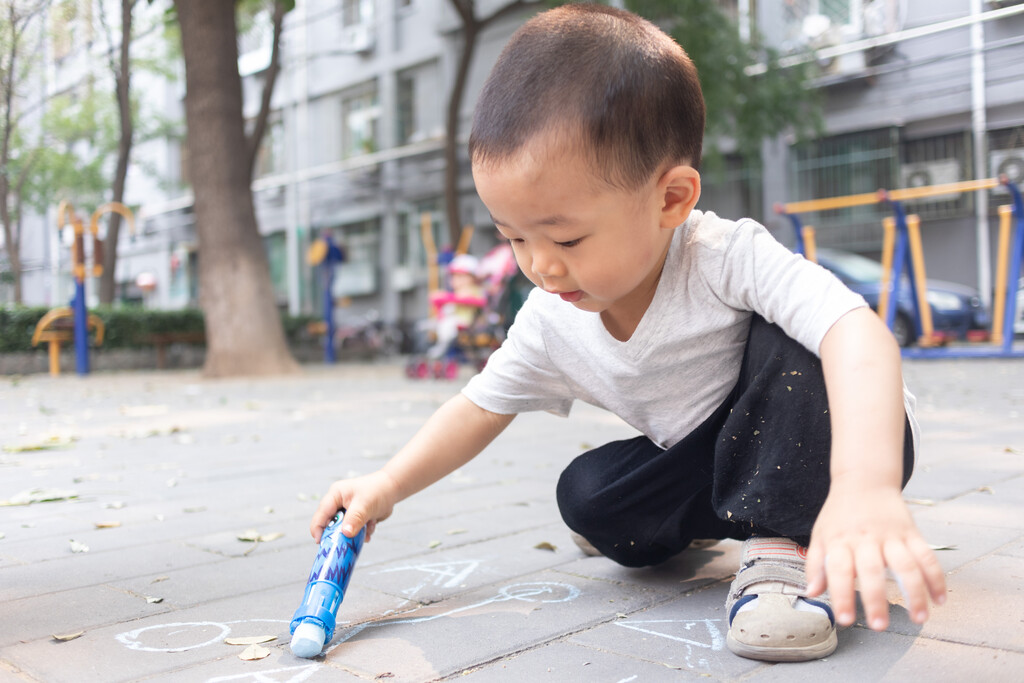 一个小男孩坐在地上用粉笔写字图片