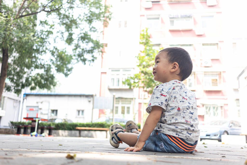 一个小男孩坐在院子里玩玩具车图片