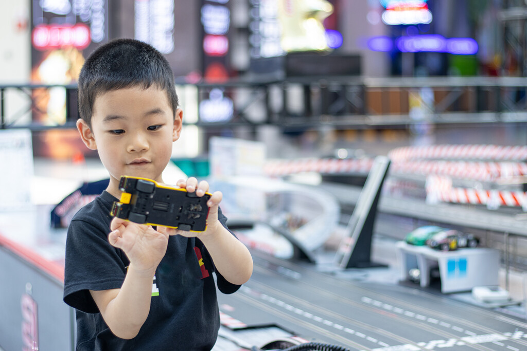 一个小男孩在游戏厅玩赛车玩具图片