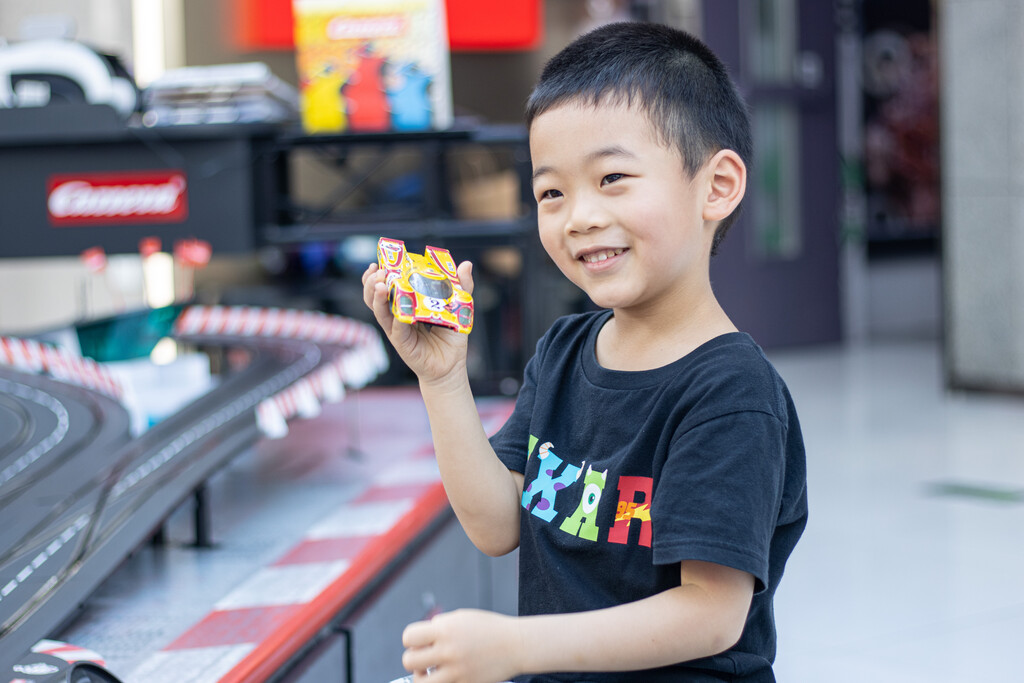 一个小男孩在游戏厅玩赛车玩具图片