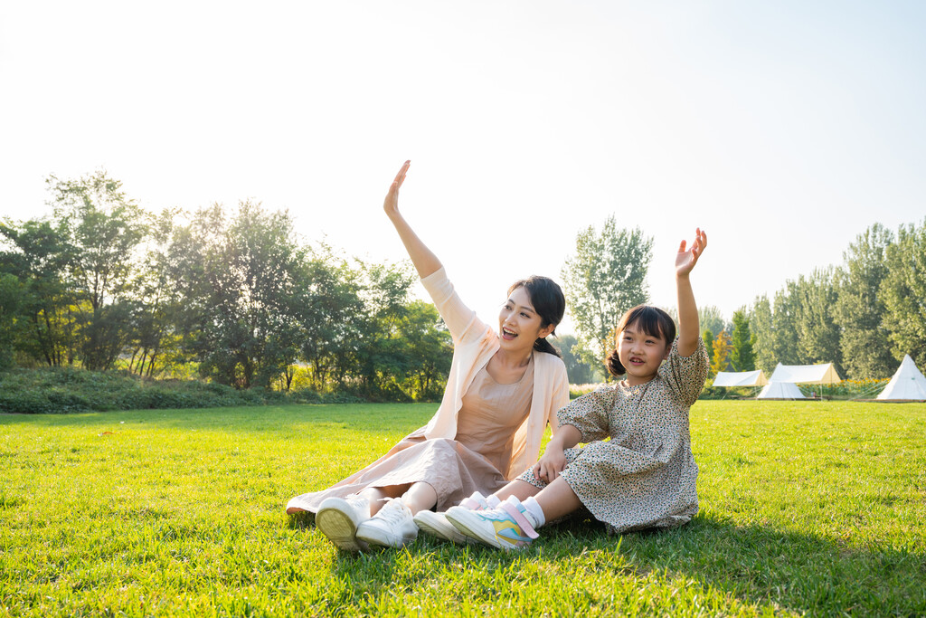 妈妈和女儿在草地上做打招呼