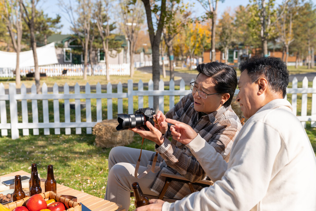 两个老年男人坐在露营地看数码相机图片