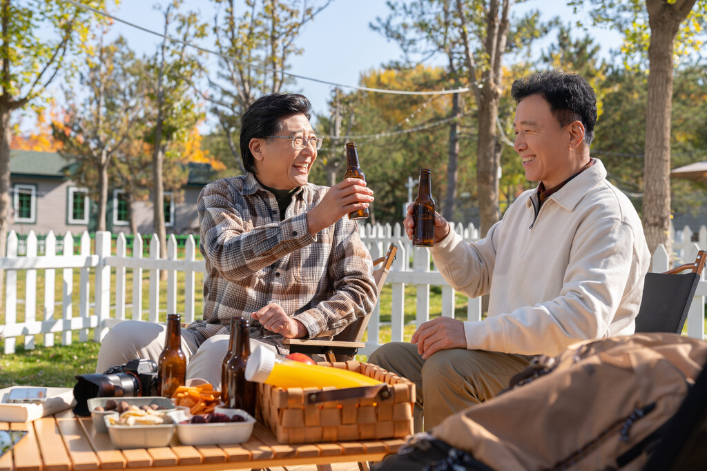 两个老年男人坐在露营地喝啤酒