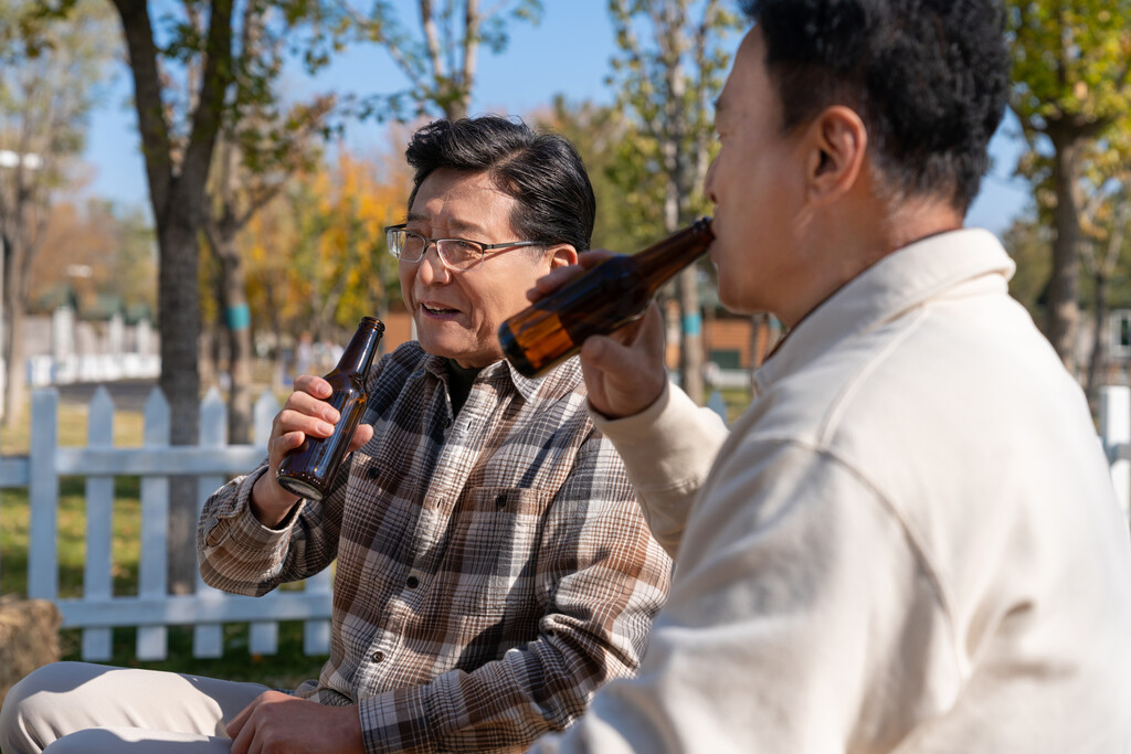 两个老年男人坐在露营地喝啤酒