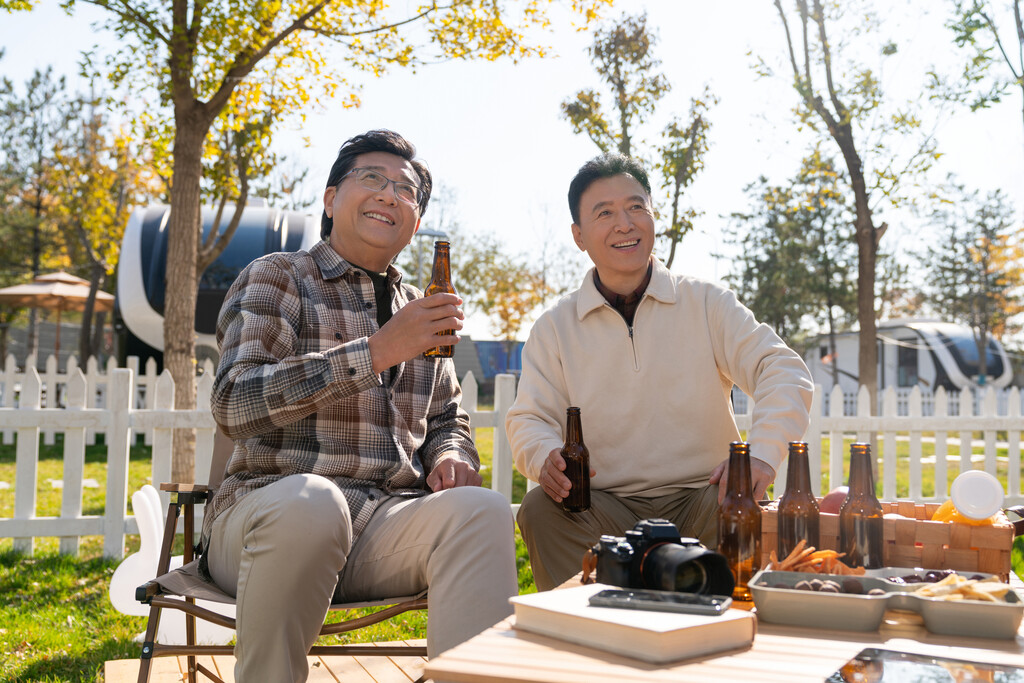 两个老年男人坐在露营地喝啤酒