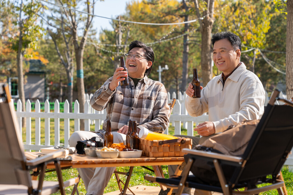 两个老年男人坐在露营地喝啤酒