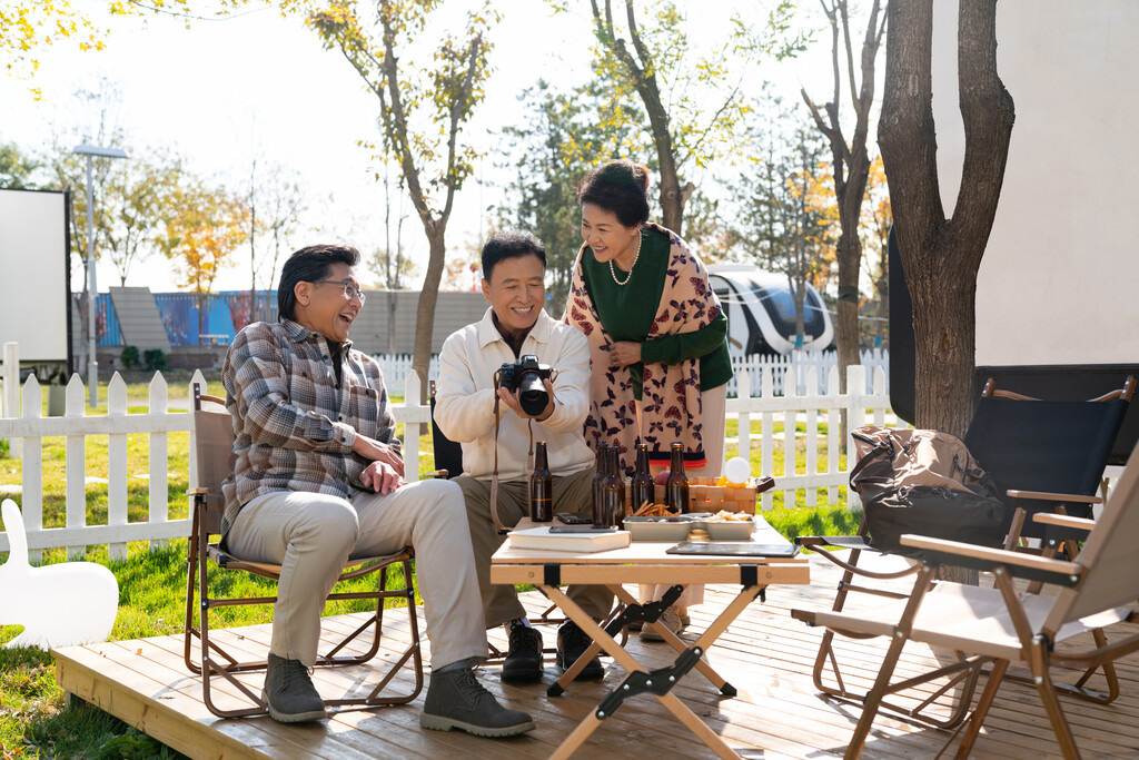 一群中老年人坐在露营地看数码相机图片