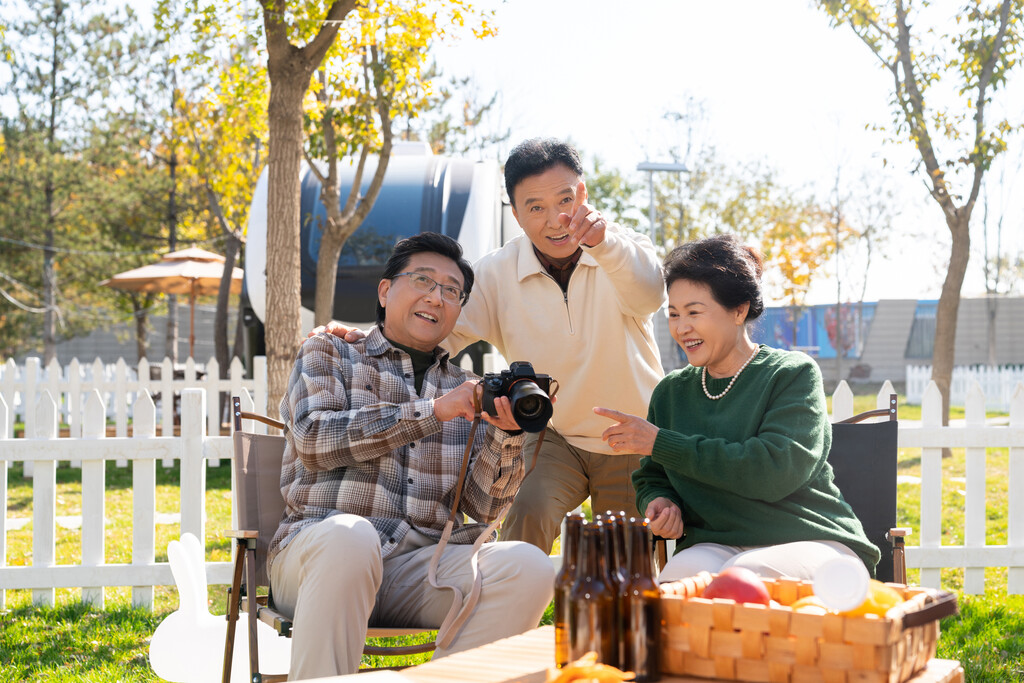 一群中老年人坐在露营地看数码相机图片