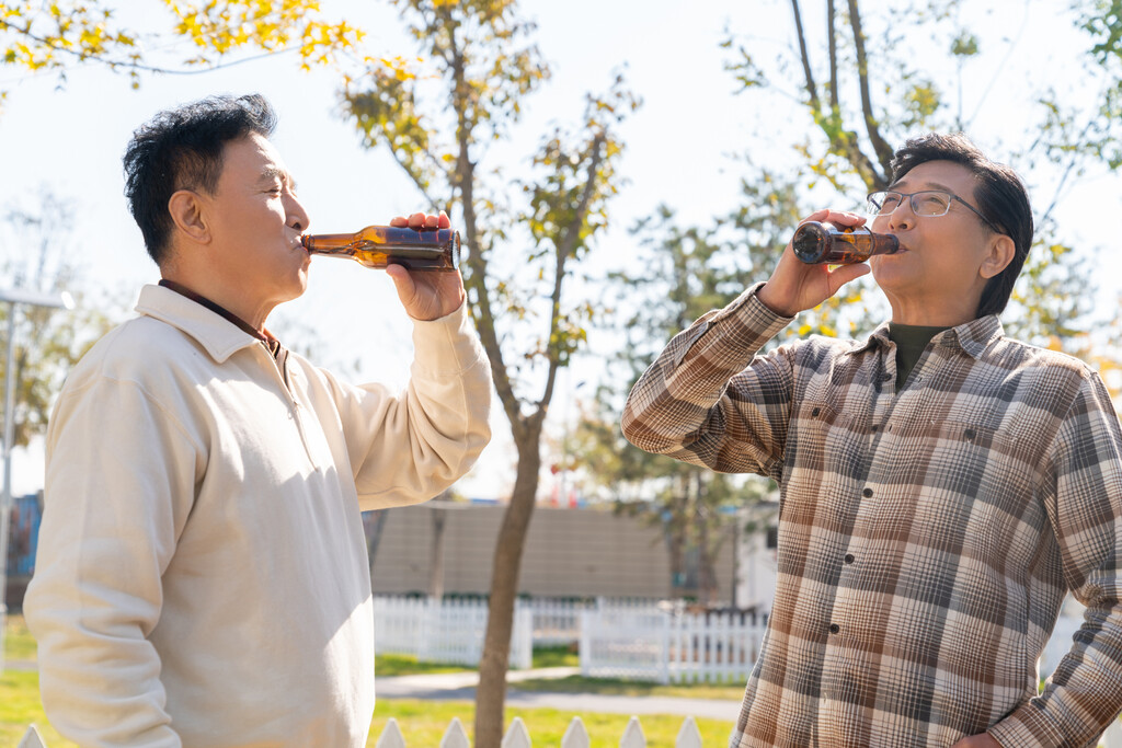 两个老年男人站在露营地喝啤酒