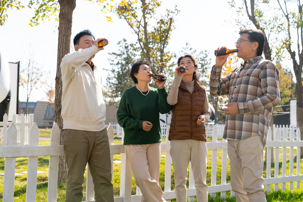 一群中老年人站在房车露营地喝啤酒