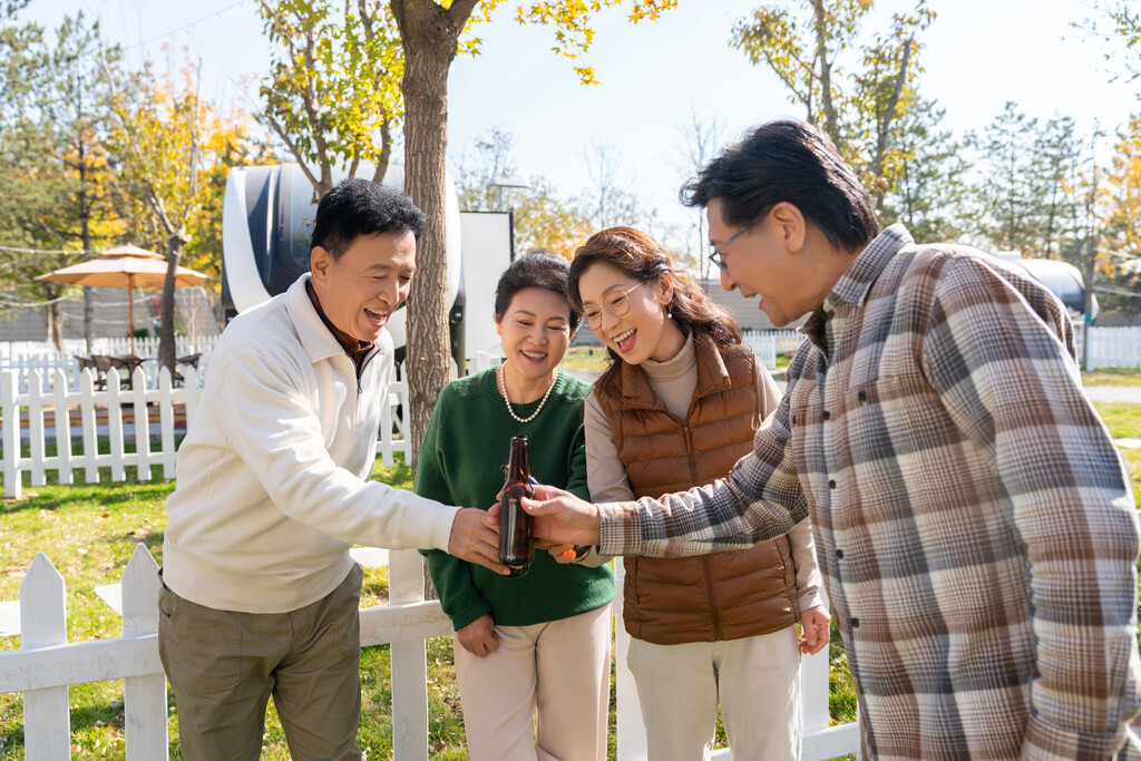 一群中老年人站在房车露营地喝啤酒图片