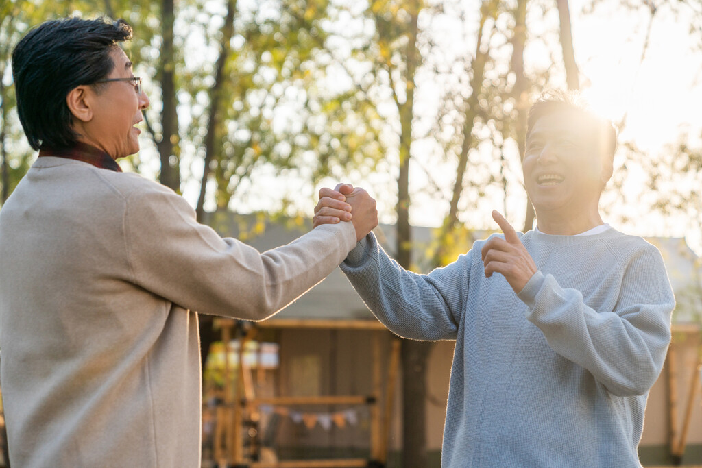 两个中老年男人开心地握手