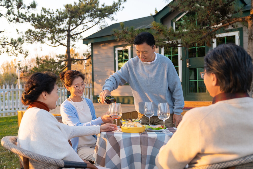 夕阳下中老年朋友在庭院里聚会喝酒聊天图片