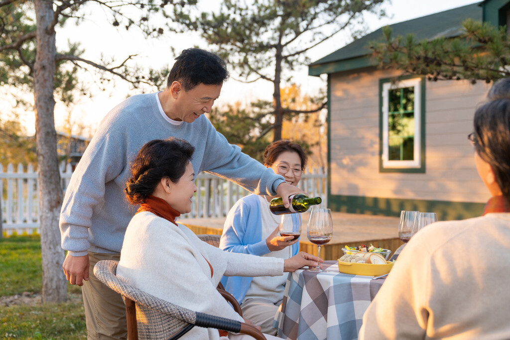 夕阳下中老年朋友在庭院里聚会喝酒聊天图片