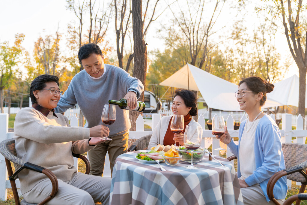 夕阳下中老年朋友在庭院里聚会喝酒聊天