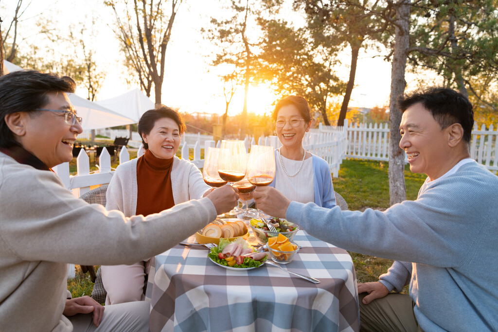 夕阳下中老年朋友在庭院里聚会喝酒聊天图片