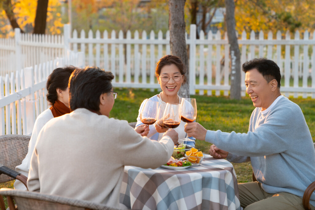 夕阳下中老年朋友在庭院里聚会喝酒聊天