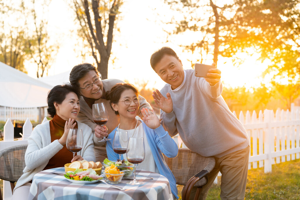 夕阳下中老年朋友在庭院里聚会喝酒拍照片图片