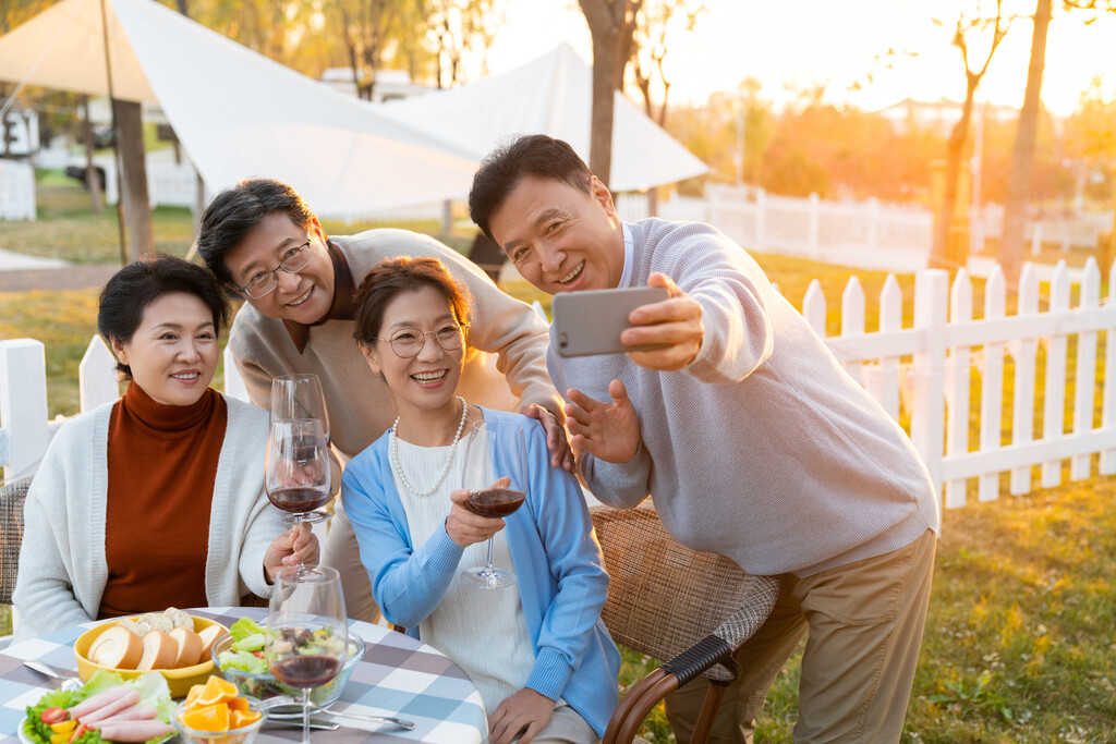 夕阳下中老年朋友在庭院里聚会喝酒拍照片图片