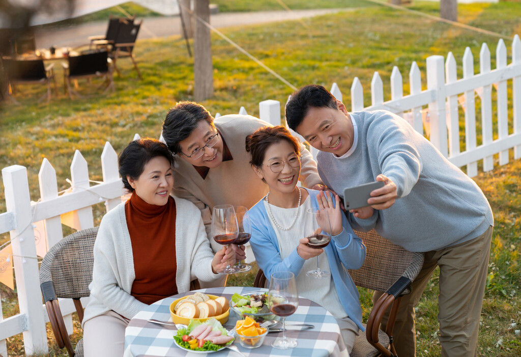 夕阳下中老年朋友在庭院里聚会喝酒拍照片图片