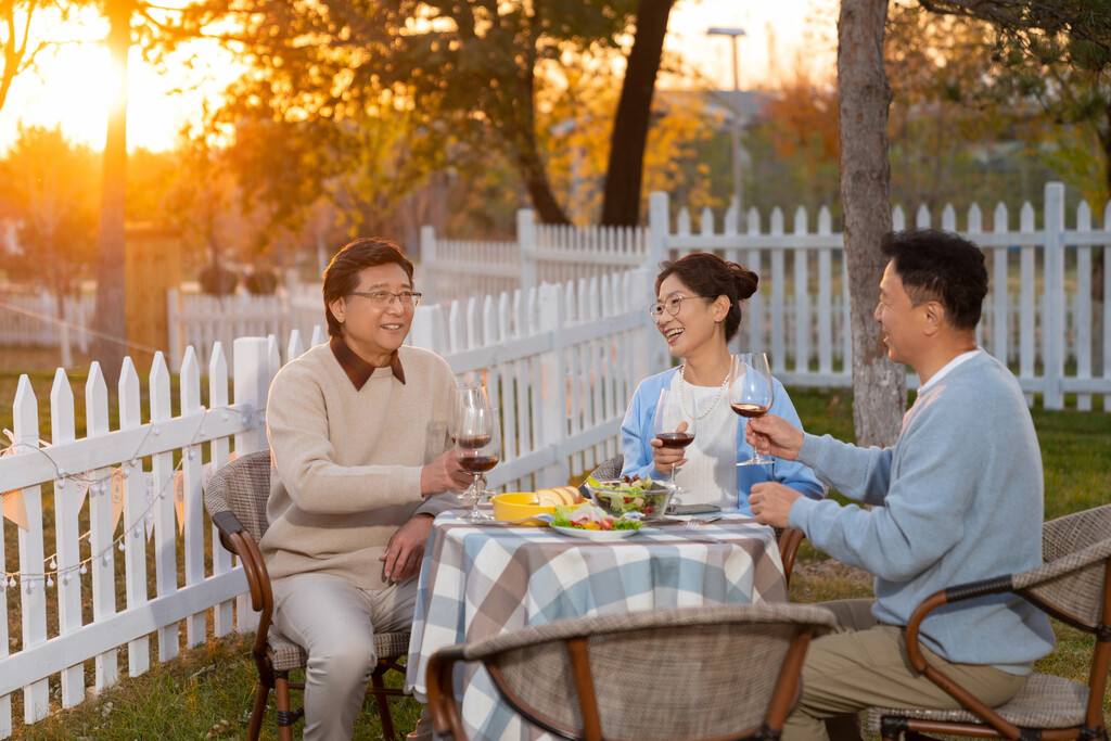 夕阳下中老年朋友在庭院里聚会喝酒聊天图片