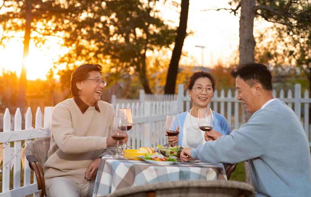 夕阳下中老年朋友在庭院里聚会喝酒聊天图片