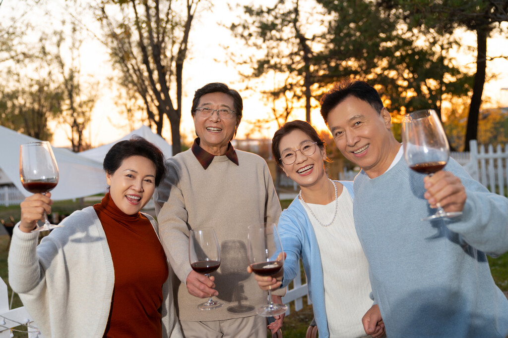 夕阳下中老年朋友在庭院里聚会喝酒聊天图片