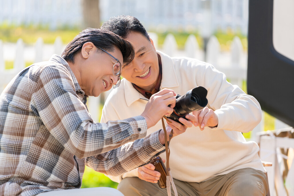 两个老年男人坐在露营地看数码相机图片