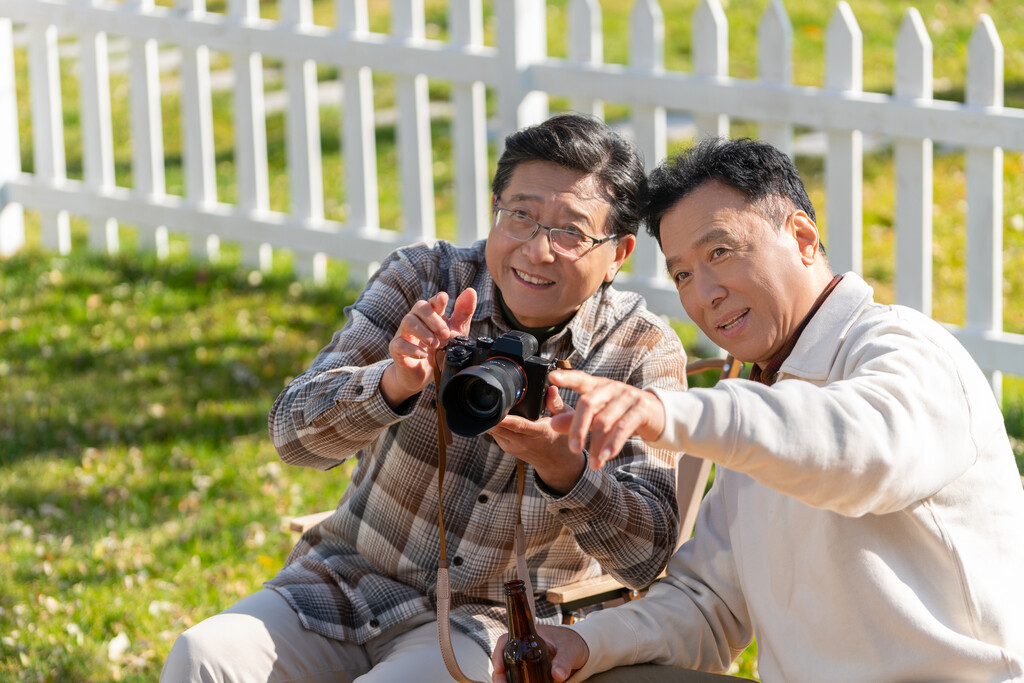 两个老年男人坐在露营地看数码相机图片